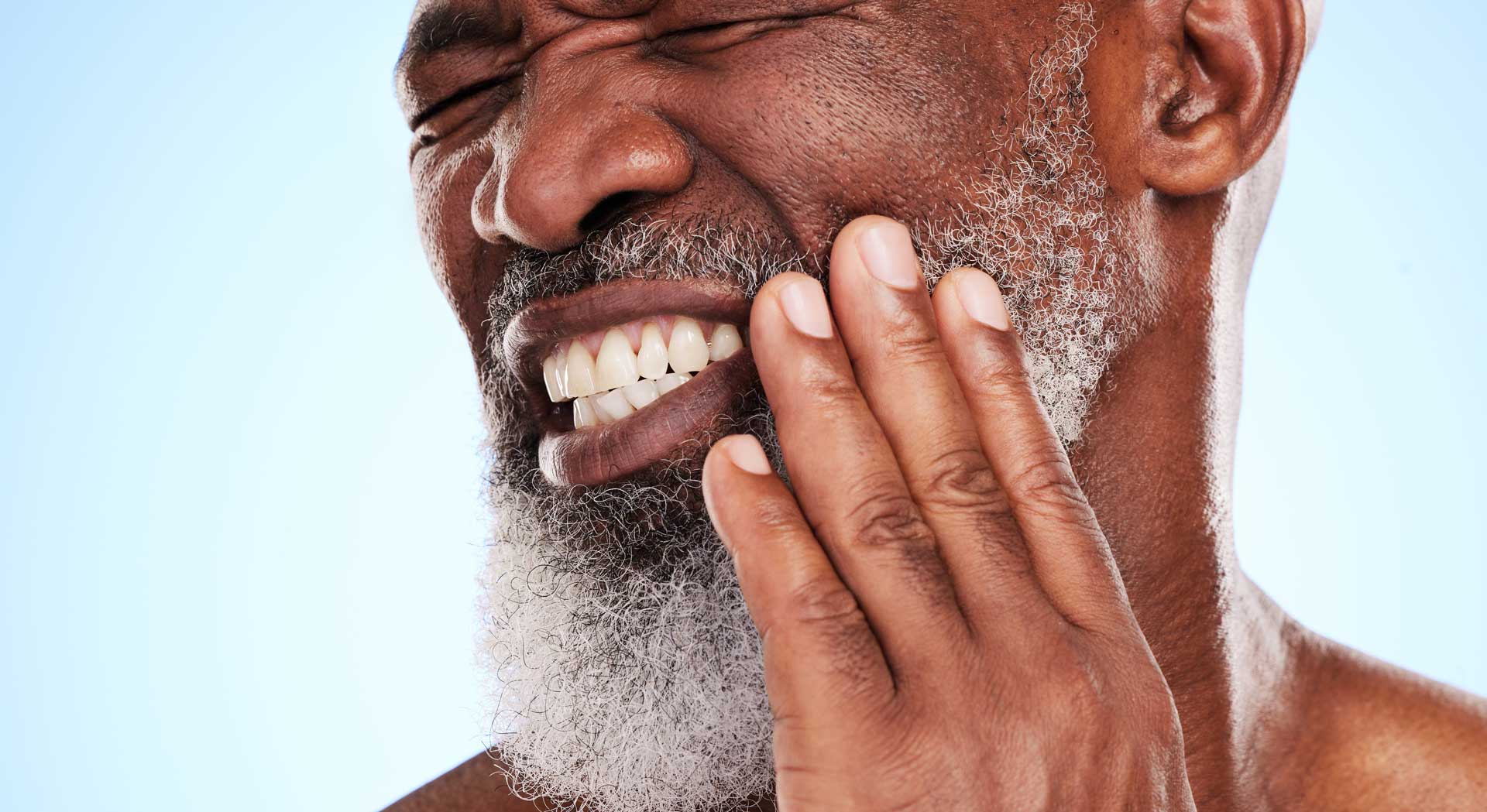 Man wincing and holding his cheek because of jaw pain